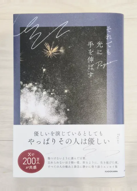 Payao『それでも光に手を伸ばす』の書影。淡い木目の上に置かれた本の表紙と、帯の「やっぱりその人は優しい」の文字